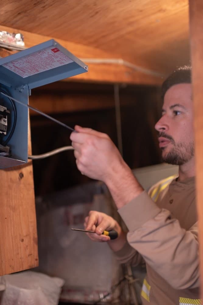Josiah Hirsh working inside a small breaker box with its cover open